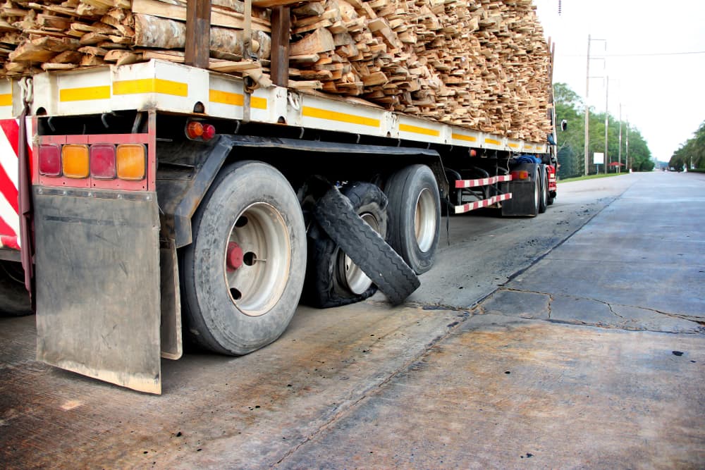 Burst tires on an 18-wheeler semi-truck by the highway after a high-speed explosion.